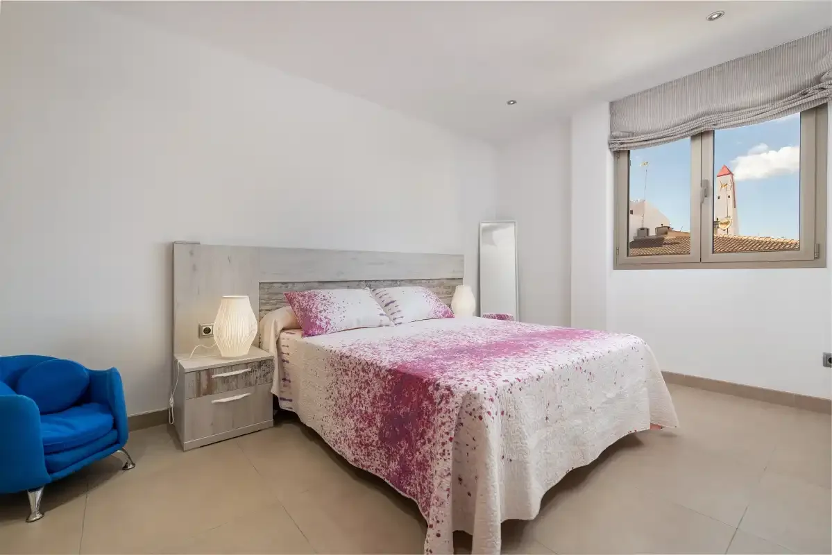 A bedroom with a double bed dressed in a pink and white cover.