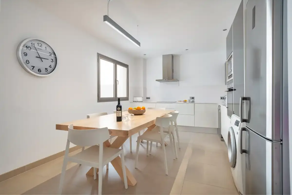 A bright kitchen and dining area with a wooden table and white cabinetry.