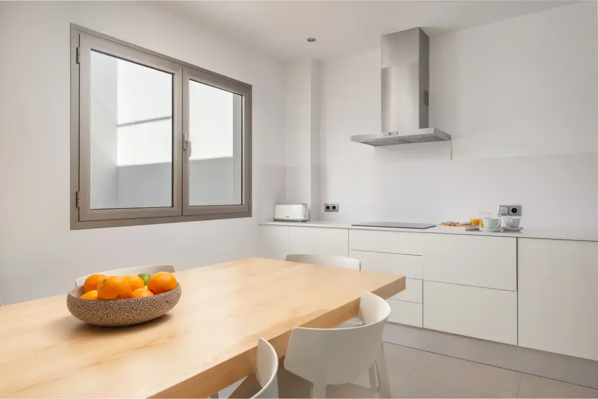 A bright kitchen with a wooden dining table and white cabinetry.