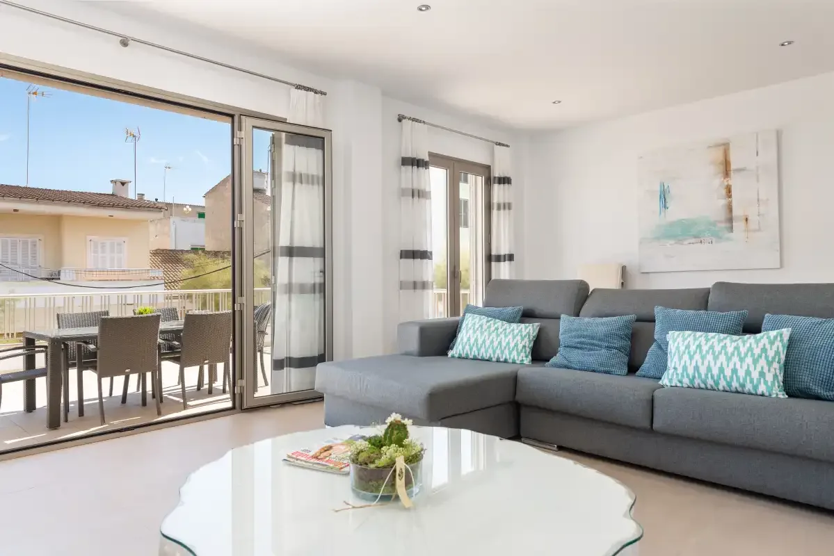 A bright living room with seating beside sliding glass doors opening onto a balcony.
