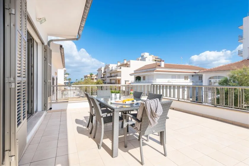 A tiled outdoor terrace with a dining table and seating overlooks nearby buildings.