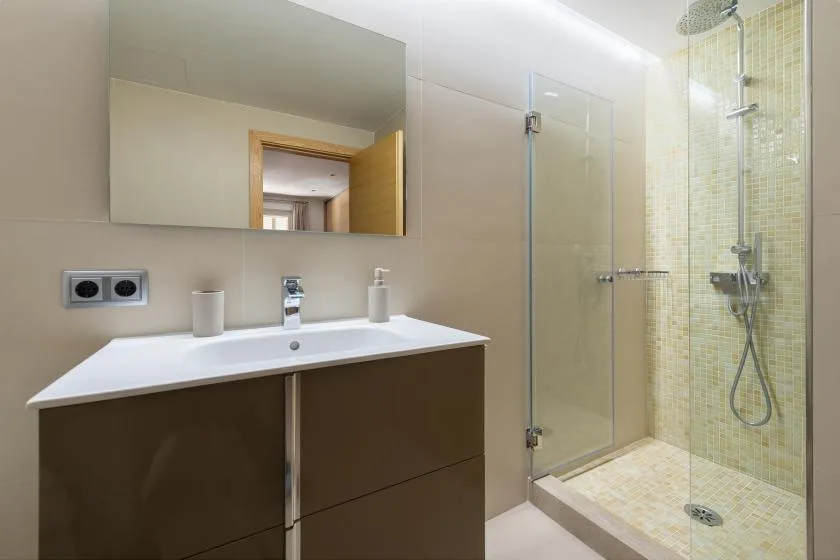 A bathroom with a vanity, mirror, and glass shower.