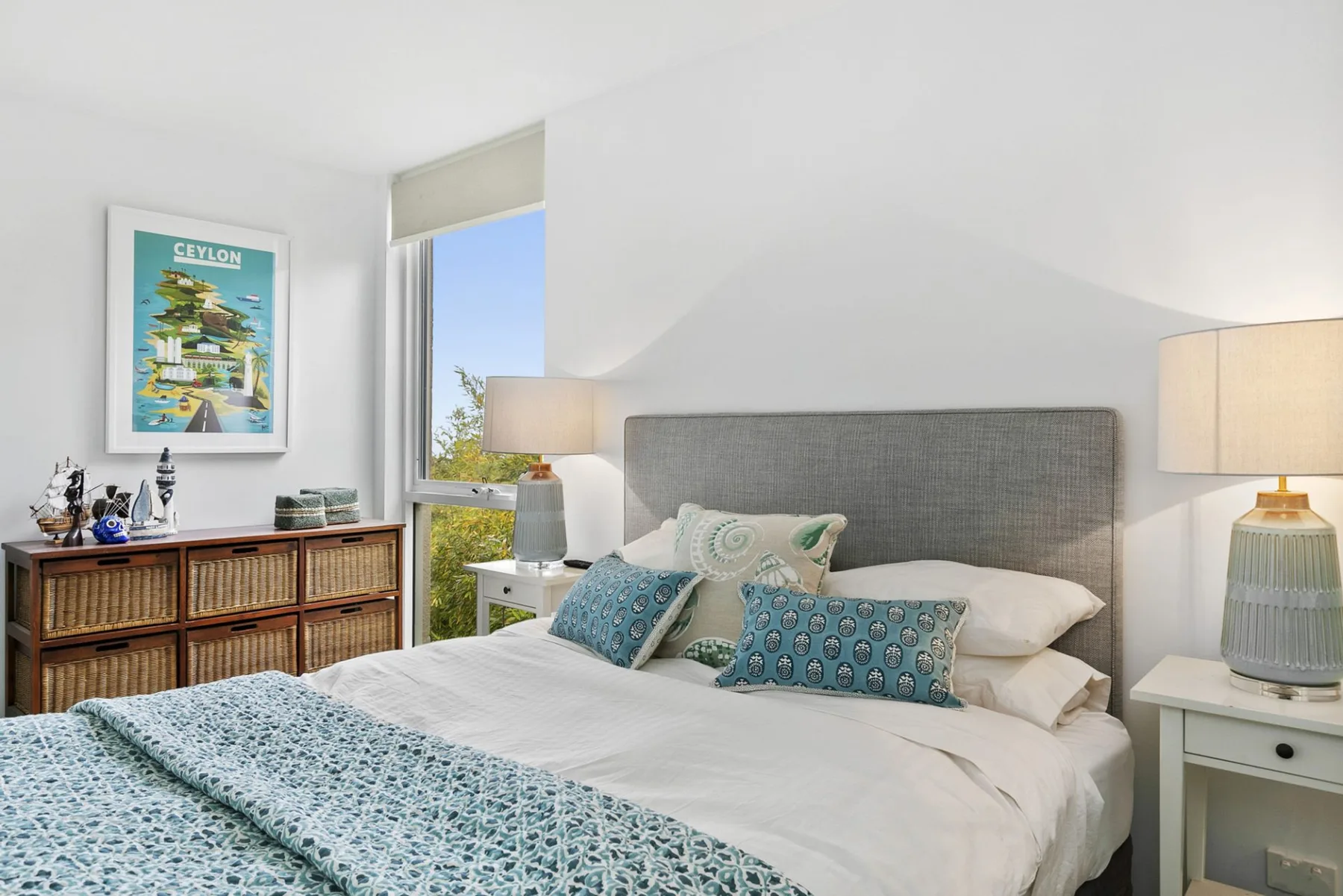 Un dormitorio con una cama bien tendida y ropa de cama azul estampada.