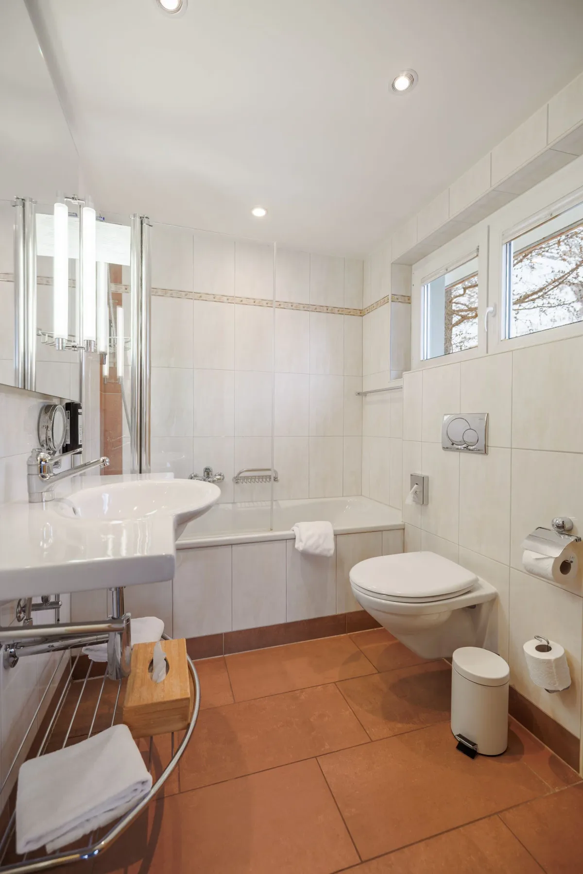 Bathroom with bathtub, sink and terracotta tile floor.