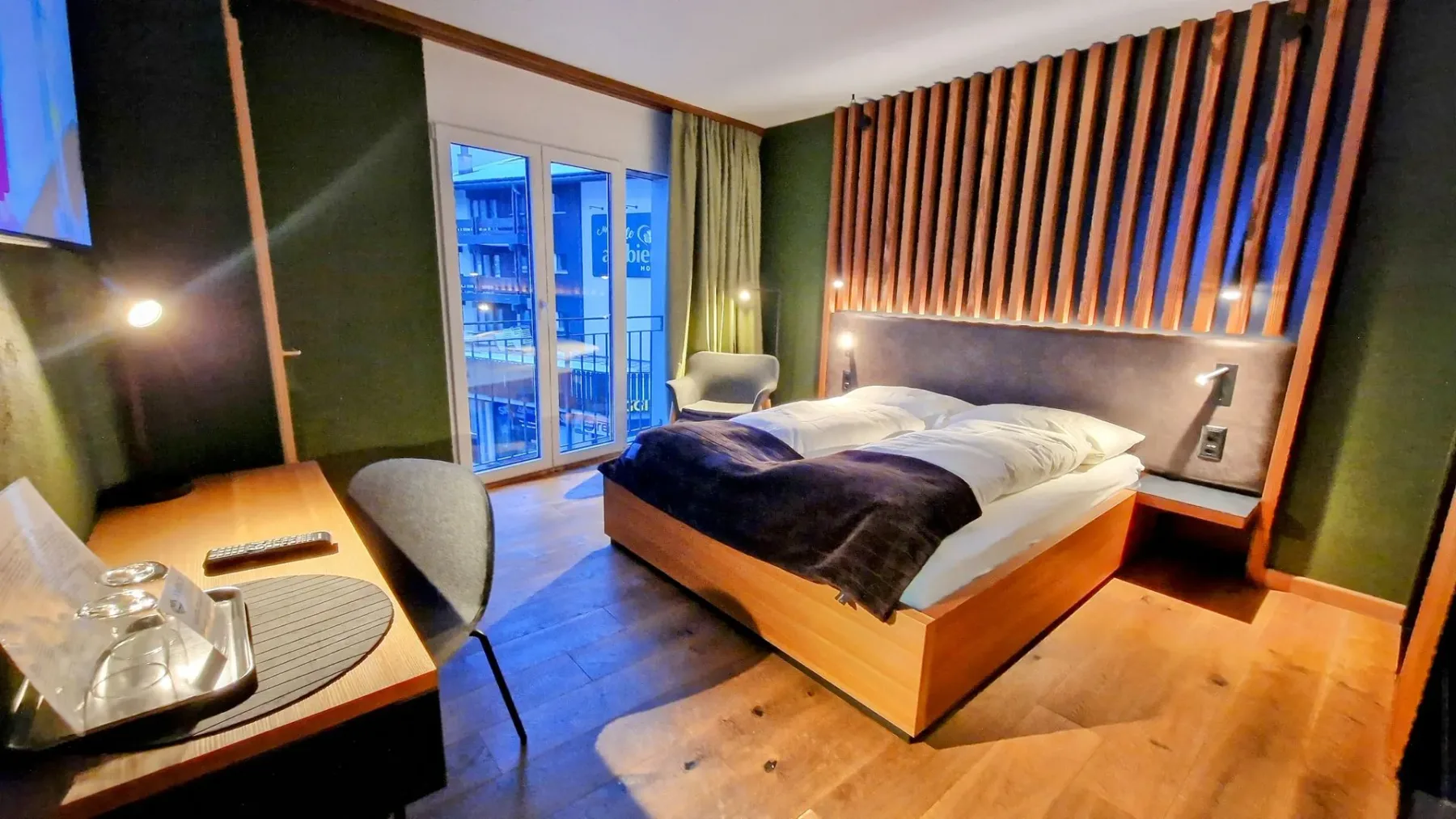 Bedroom with bed, desk and wood accent wall.