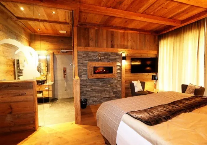 Wood-paneled bedroom with a stone fireplace.