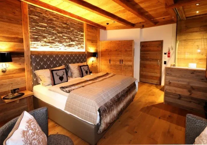 Rustic bedroom with wooden beams and a made bed.