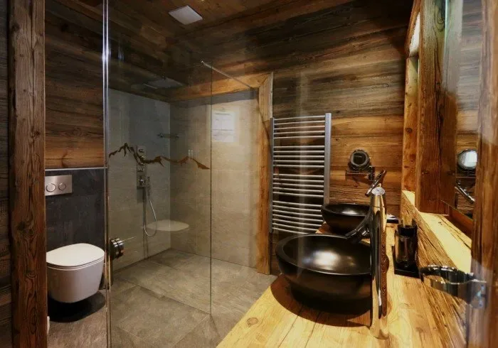 Bathroom with glass shower and wood-paneled walls.