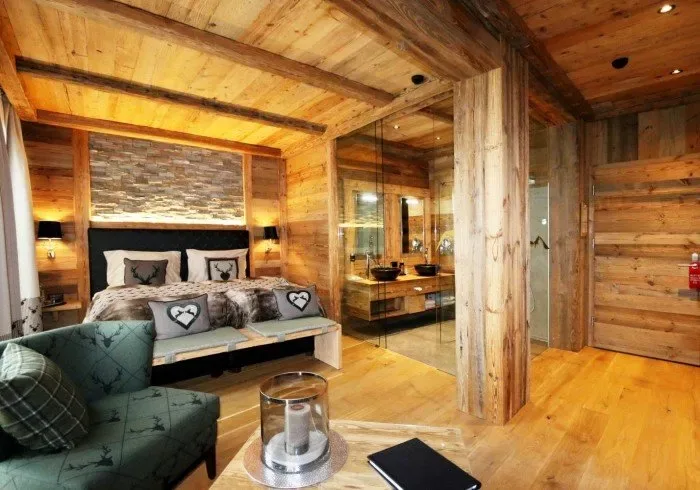 Rustic bedroom with stone fireplace and green armchair.