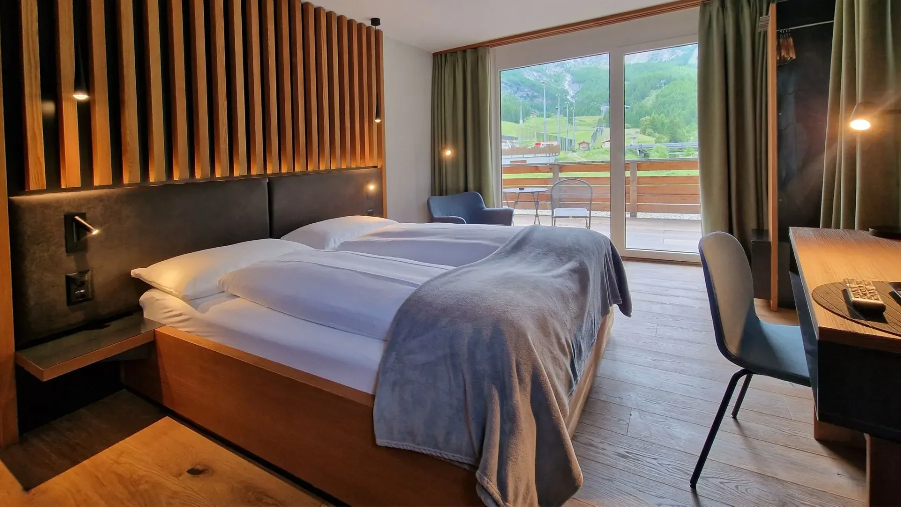 Hotel room with two beds, desk and balcony doors.