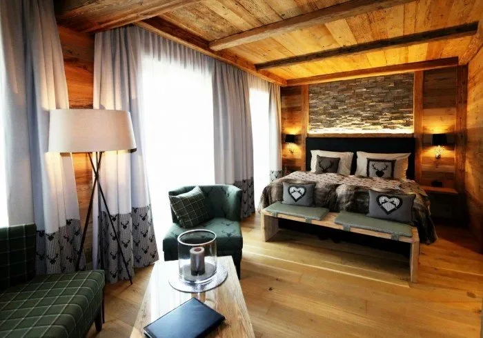 Wooden bedroom with large window, bed and armchair.