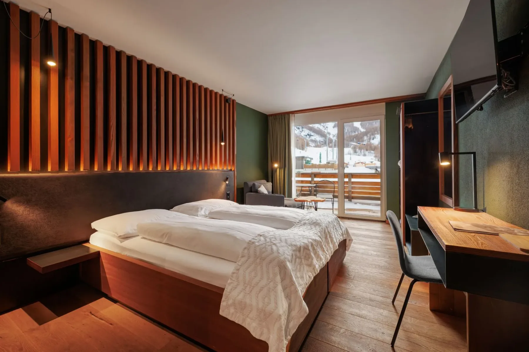 Hotel bedroom with a large bed and balcony doors.