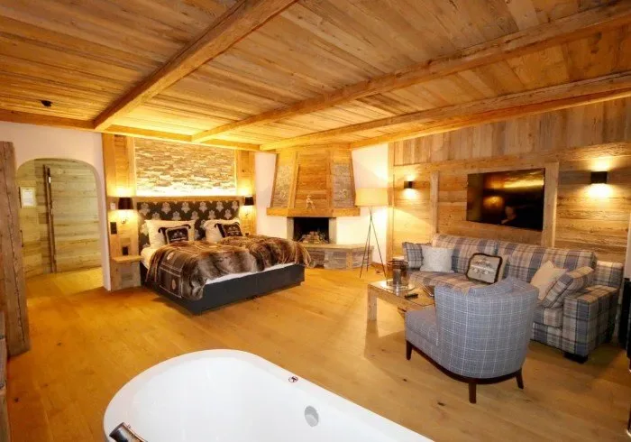 Suite bedroom with wood paneling, armchairs and a jacuzzi tub.