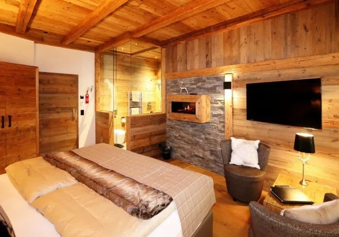 Bedroom with wooden ceiling, fireplace and bed.
