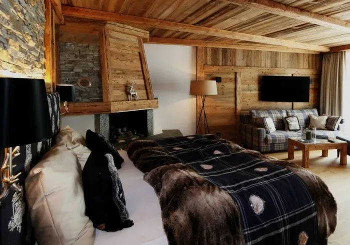 Wood-paneled bedroom with a bed, fireplace and television.