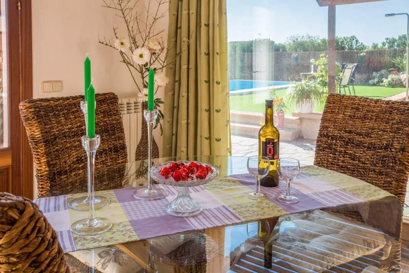 A dining table set with candles and flowers overlooks a patio and swimming pool.