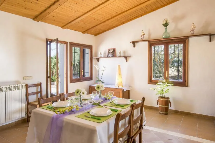 A dining room with a table set for a meal beneath a wooden ceiling.