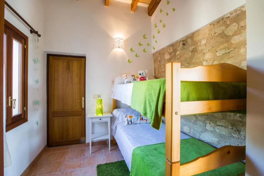 A bright bedroom with a wooden bunk bed and a window beside it.
