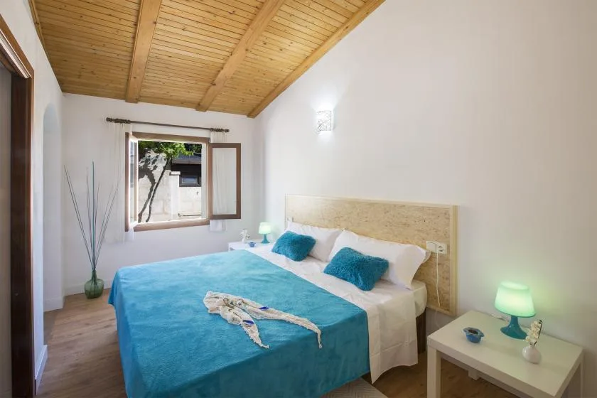 A bedroom with a bed covered in a bright blue blanket beneath a sloped wooden ceiling.