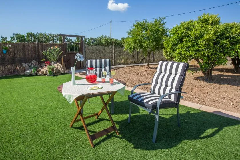 A garden seating area with a small table and striped chairs on the lawn.
