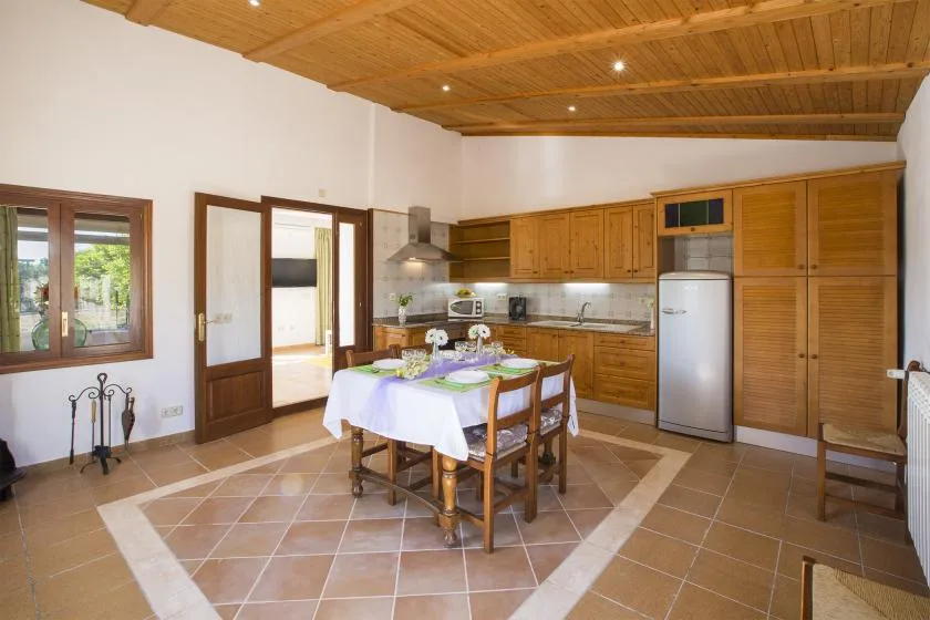 A kitchen and dining area with wooden cabinetry and a table set with a white cloth.