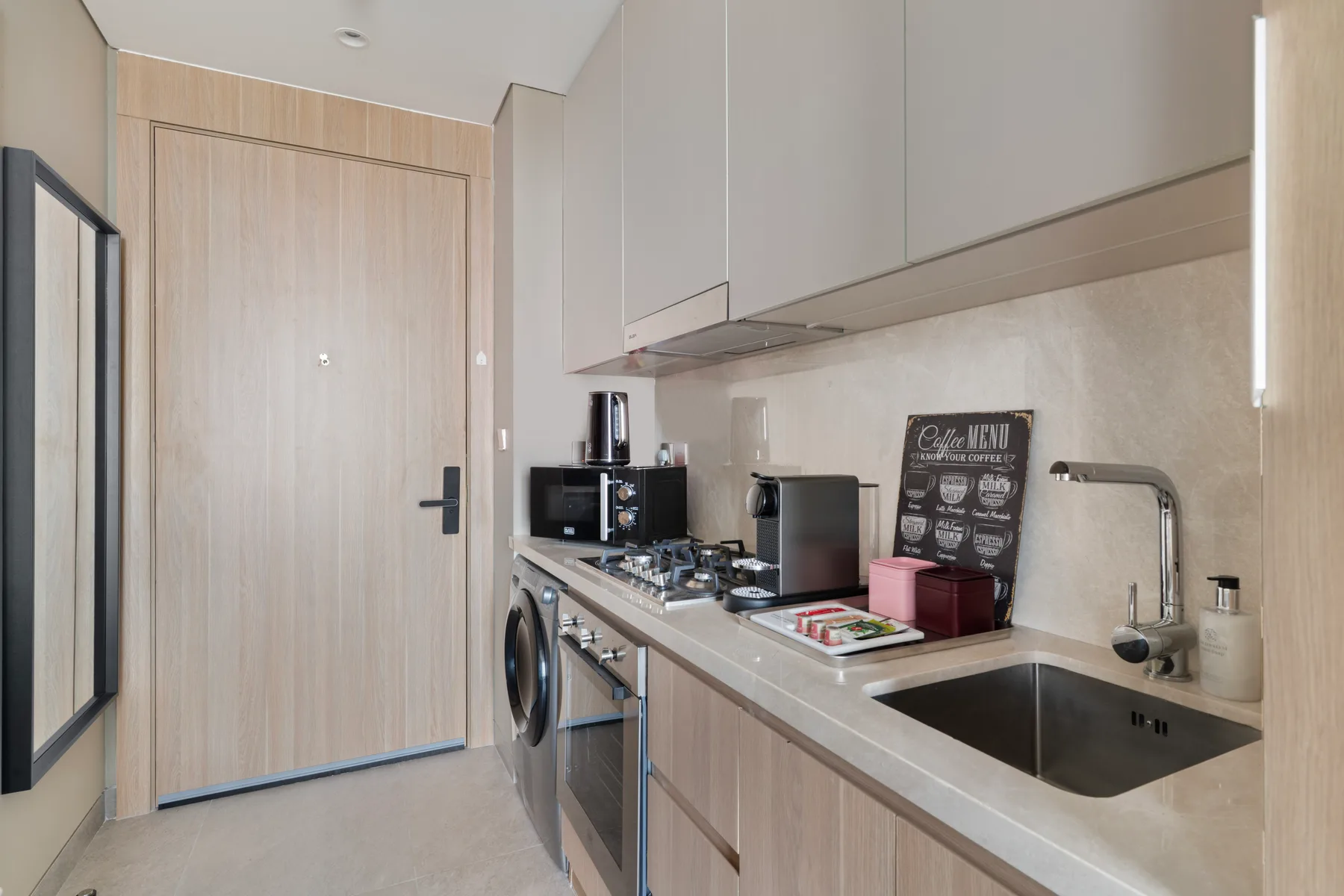Una cocina compacta con gabinetes claros, una encimera y un fregadero.