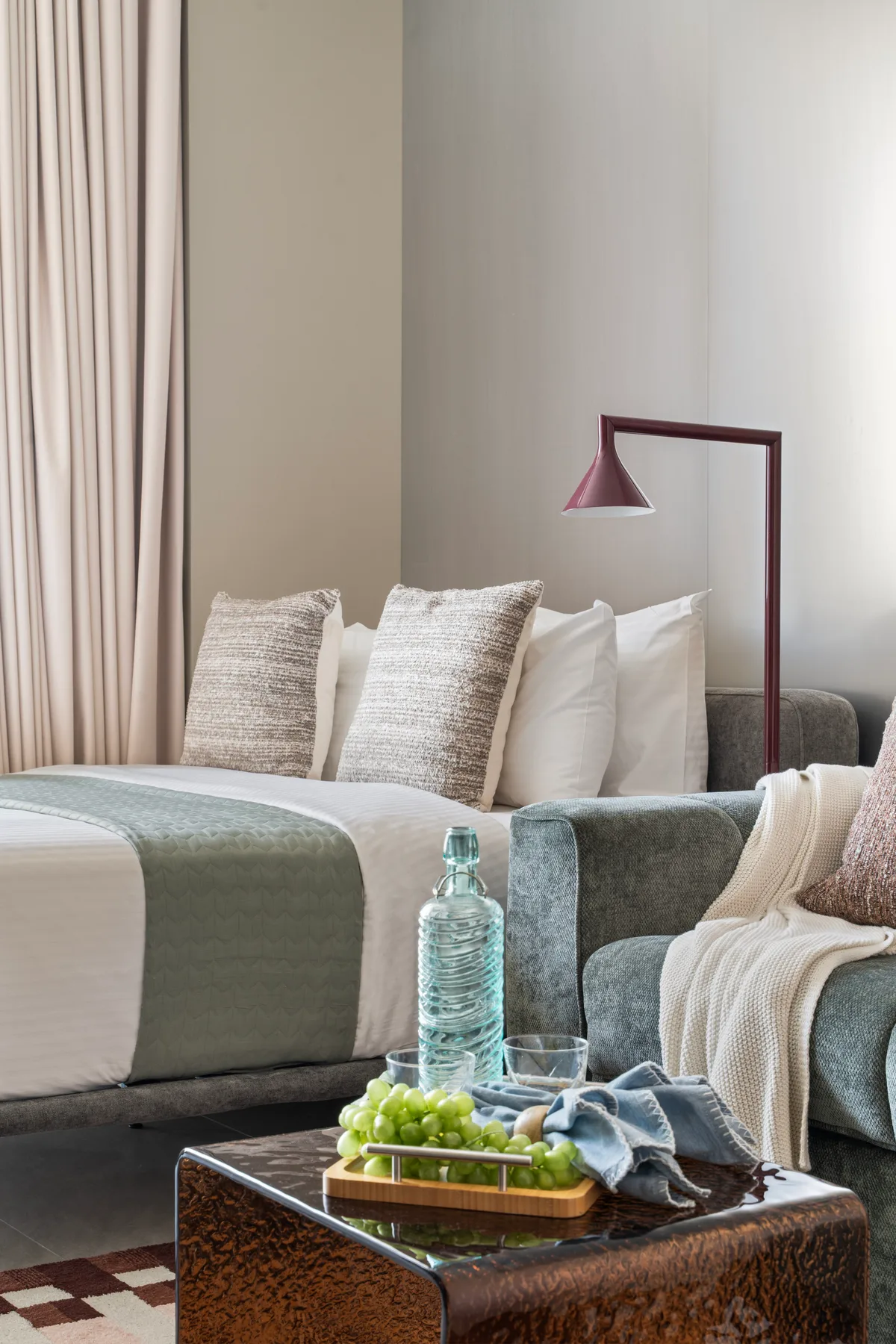 Una cama bien arreglada con almohadas superpuestas y una lámpara junto a la cama.