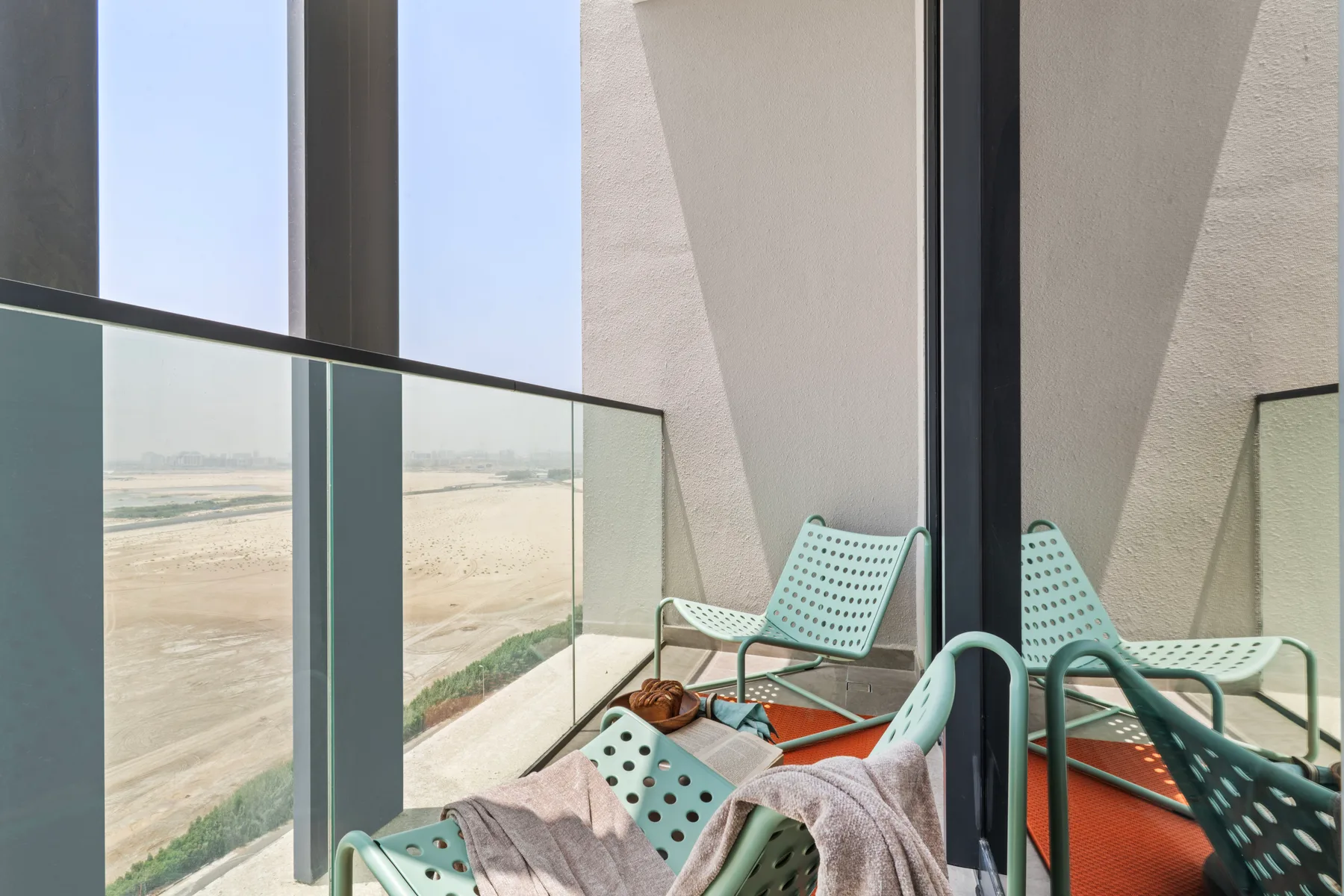 Una zona de asientos en el balcón, con barandillas de vidrio y vistas al paisaje.