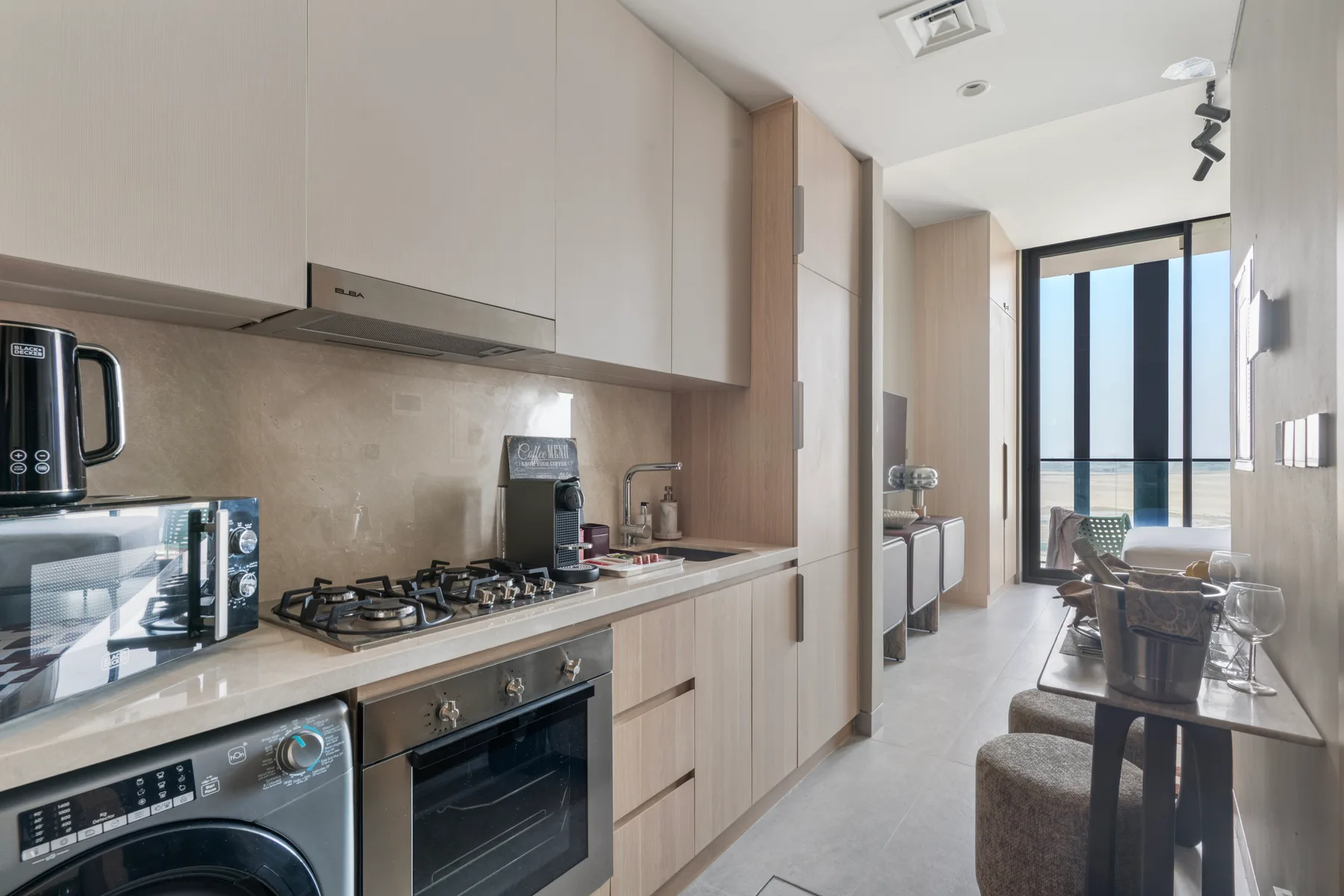 Una cocina moderna se abre a un comedor junto a ventanas altas.