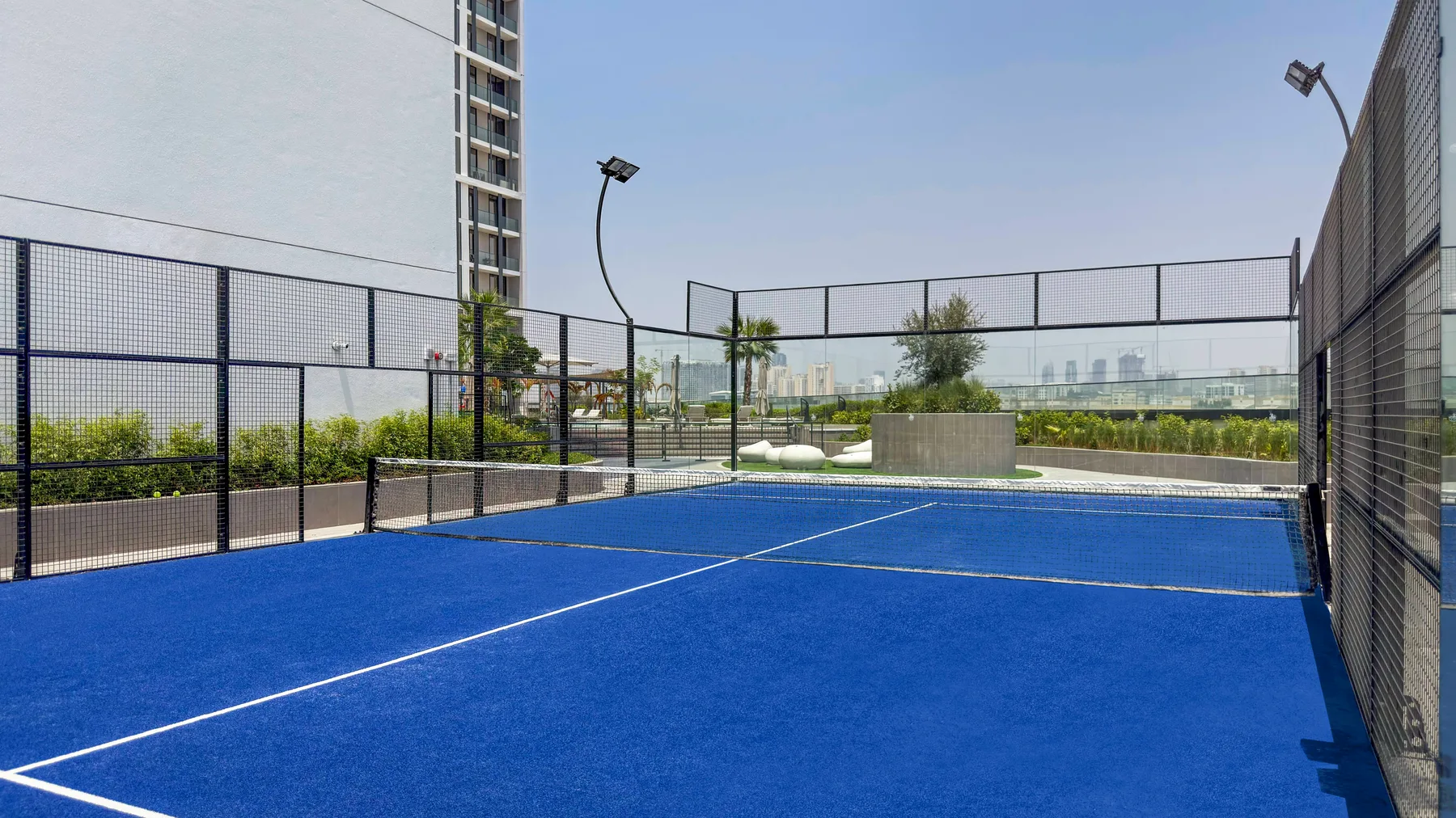 Una cancha de tenis azul rodeada por una alta valla de malla.