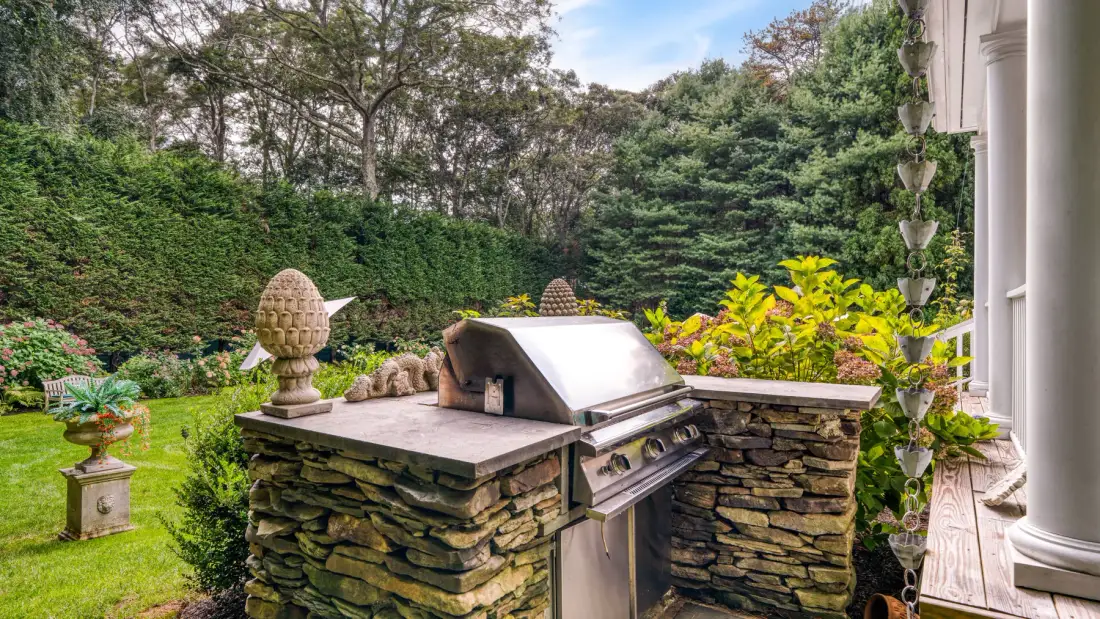Un patio ajardinado con una parrilla integrada rodeada de vegetación.