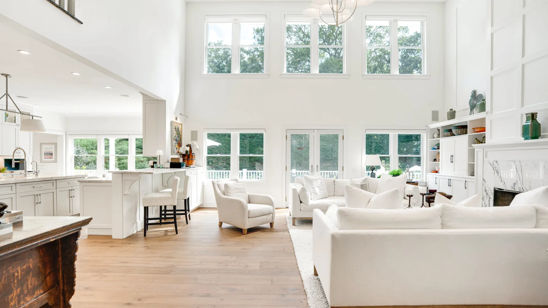 Una luminosa sala de estar de concepto abierto con asientos blancos y ventanas grandes.