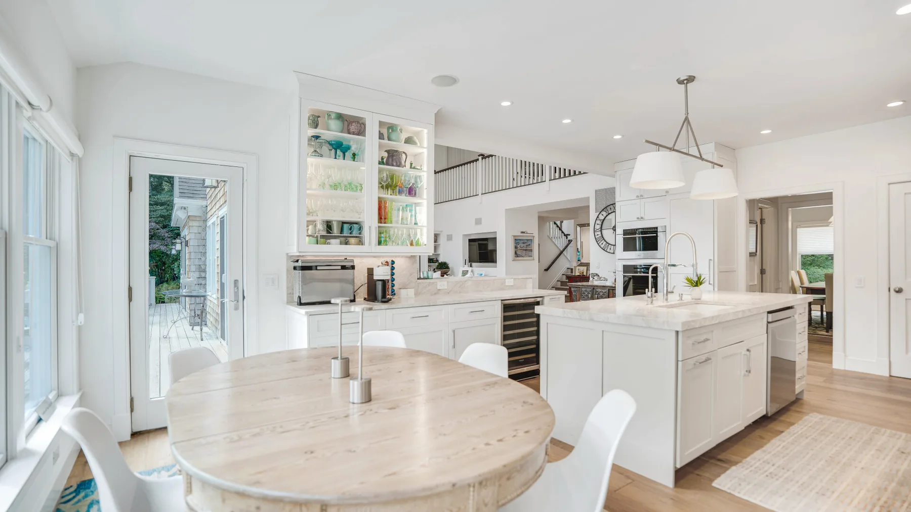 Una cocina luminosa con comedor cuenta con una isla amplia y una mesa redonda de madera.