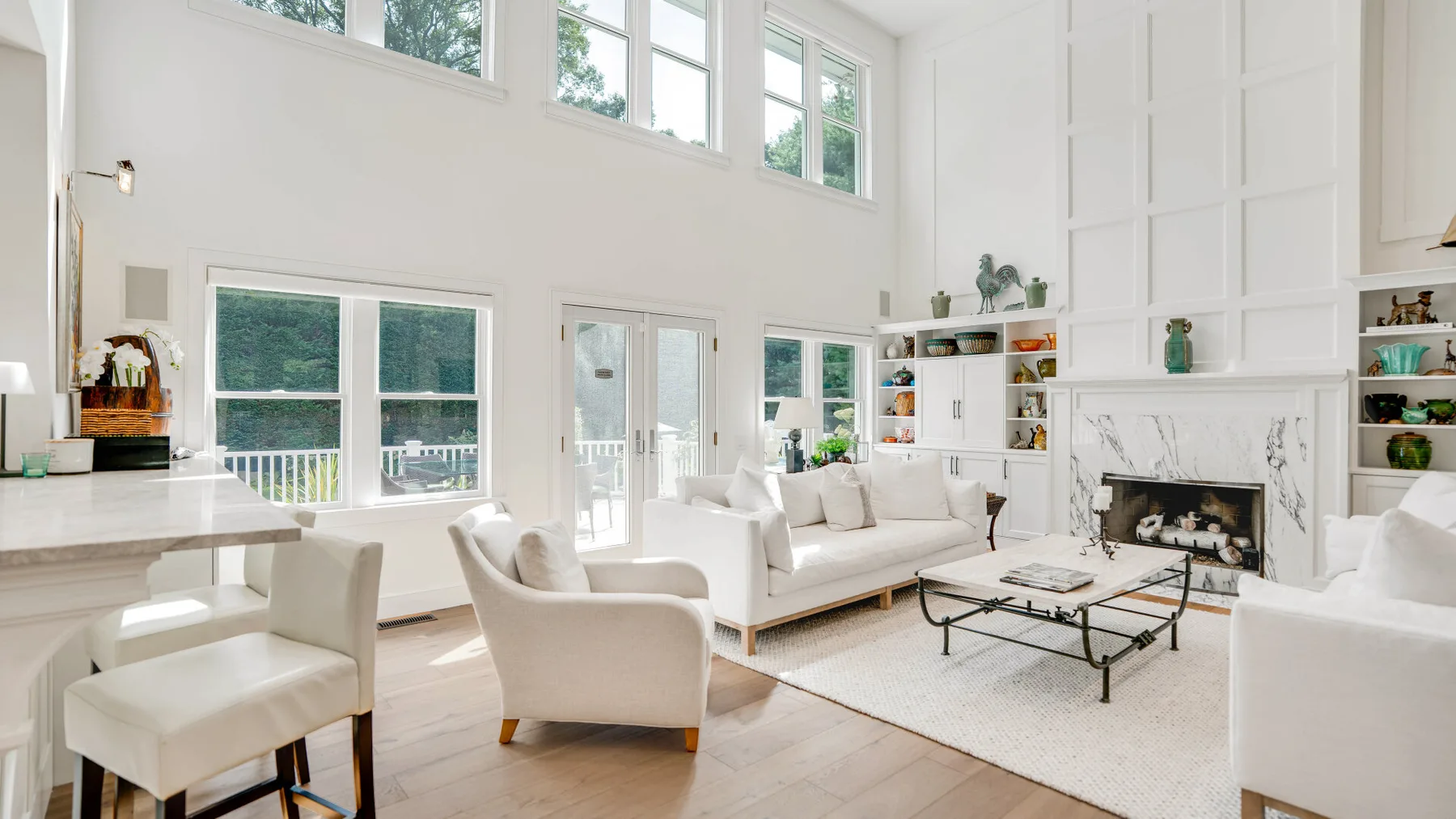 Una sala luminosa con asientos blancos, una chimenea y ventanas altas.