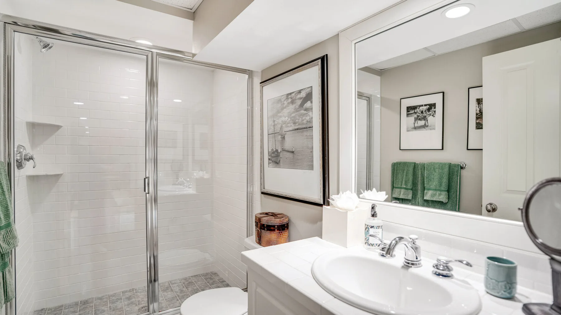 Un baño luminoso con una ducha de vidrio y un lavabo blanco.