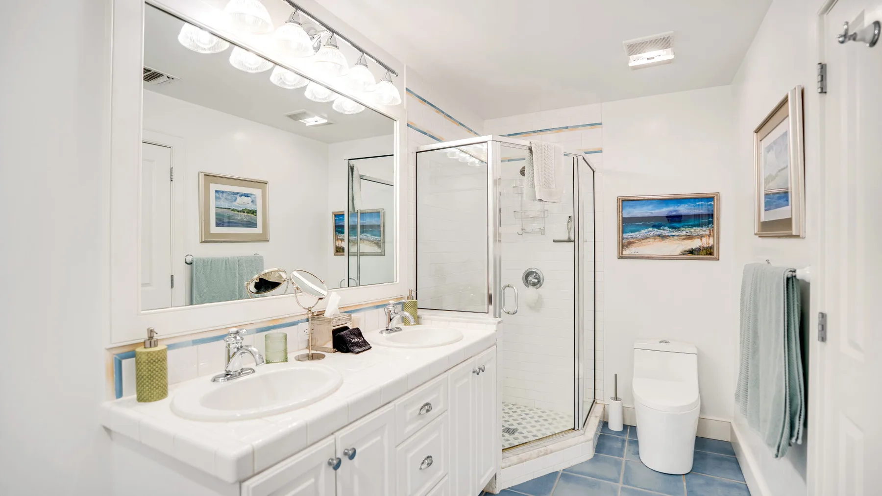 Un baño luminoso con lavabo doble y ducha de vidrio.