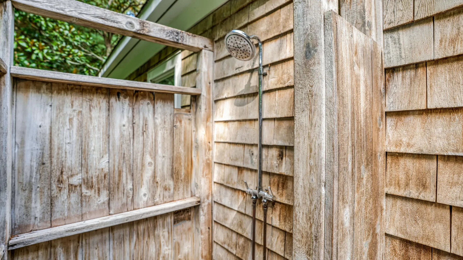 Una ducha exterior junto a una cerca de madera.