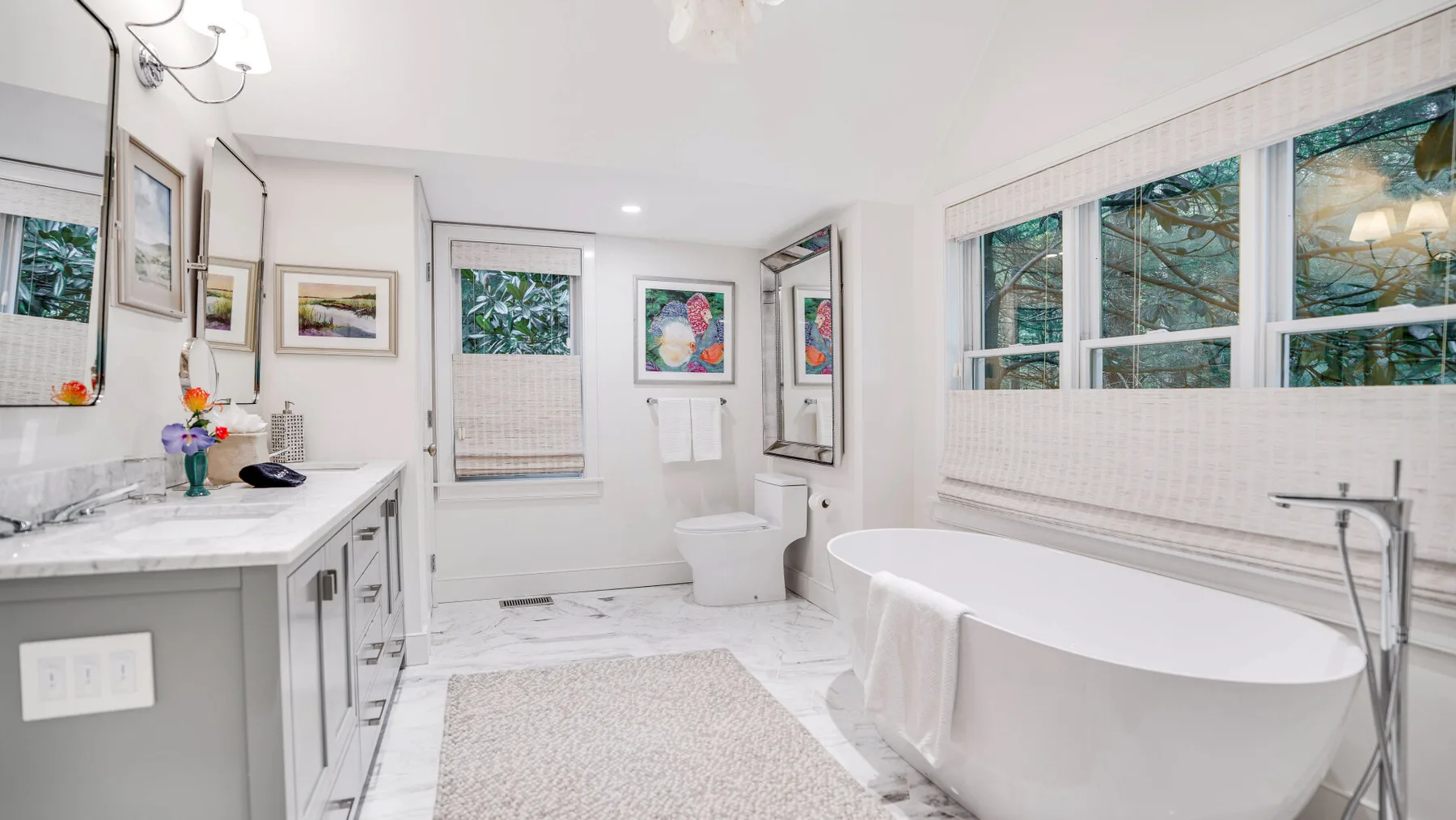 Un baño luminoso con una bañera independiente junto a grandes ventanas.