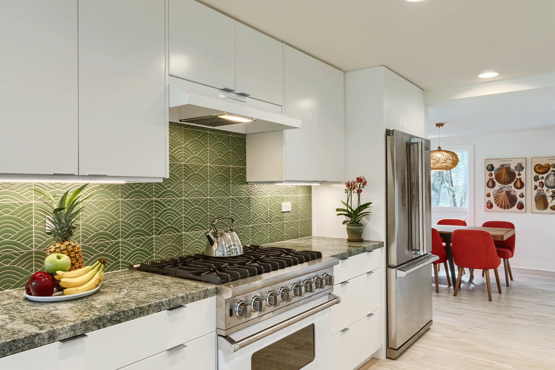 Una cocina luminosa con estufa, salpicadero verde y comedor.