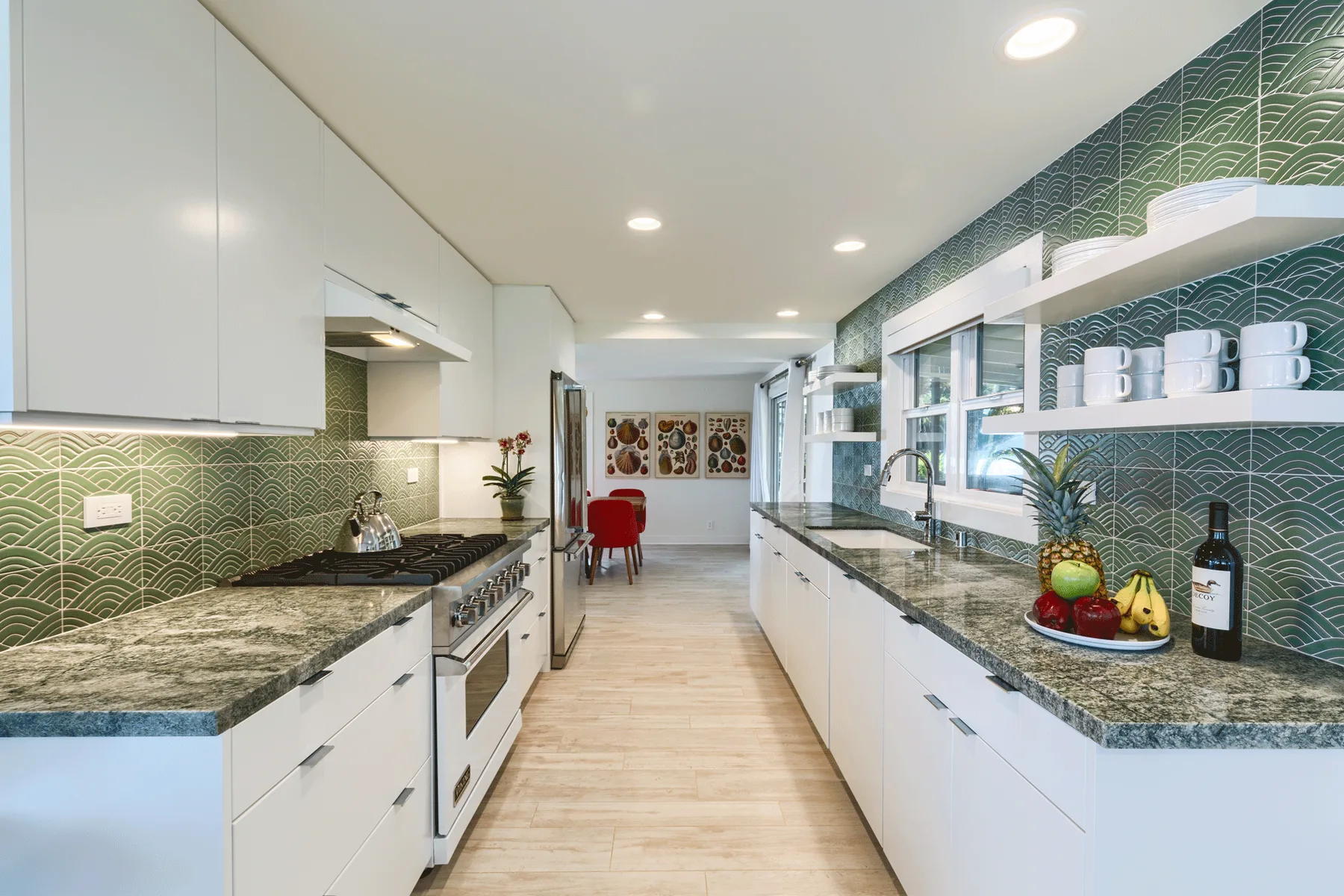 Una cocina luminosa con gabinetes blancos, salpicadero estampado y encimeras largas.