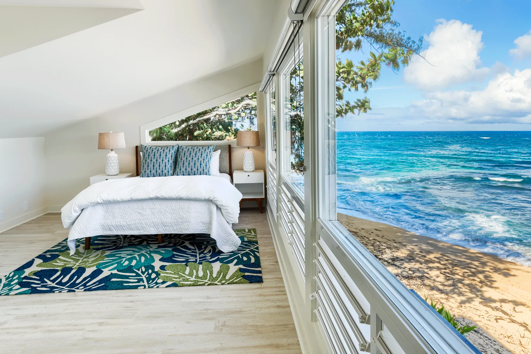 Un dormitorio con una cama junto a grandes ventanas con vistas al mar.