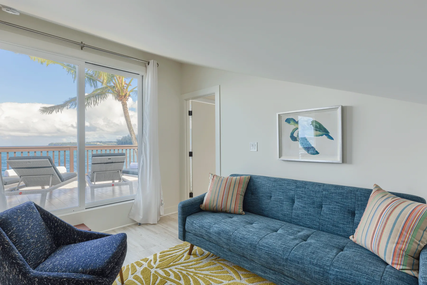 Una sala luminosa con asientos azules, una gran ventana y vistas al mar.
