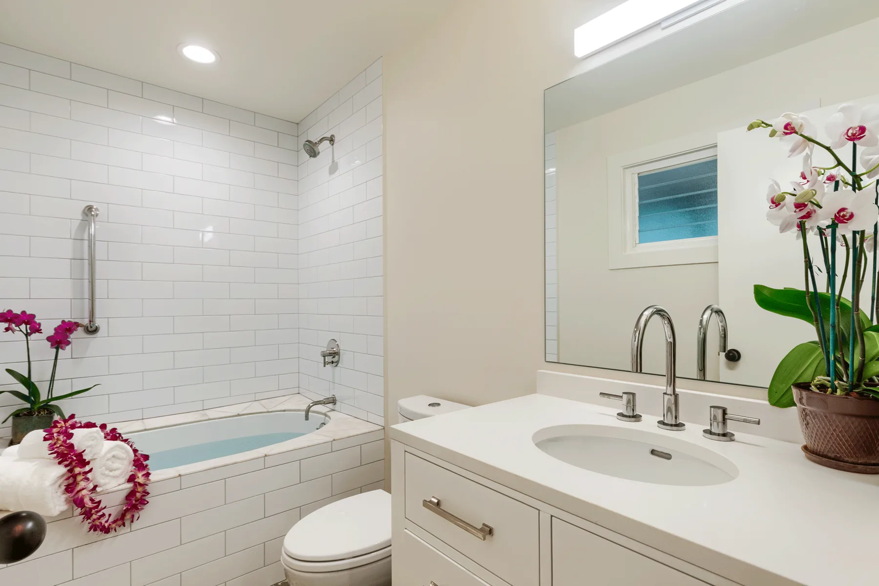Un baño luminoso con bañera revestida de azulejos y lavabo blanco.