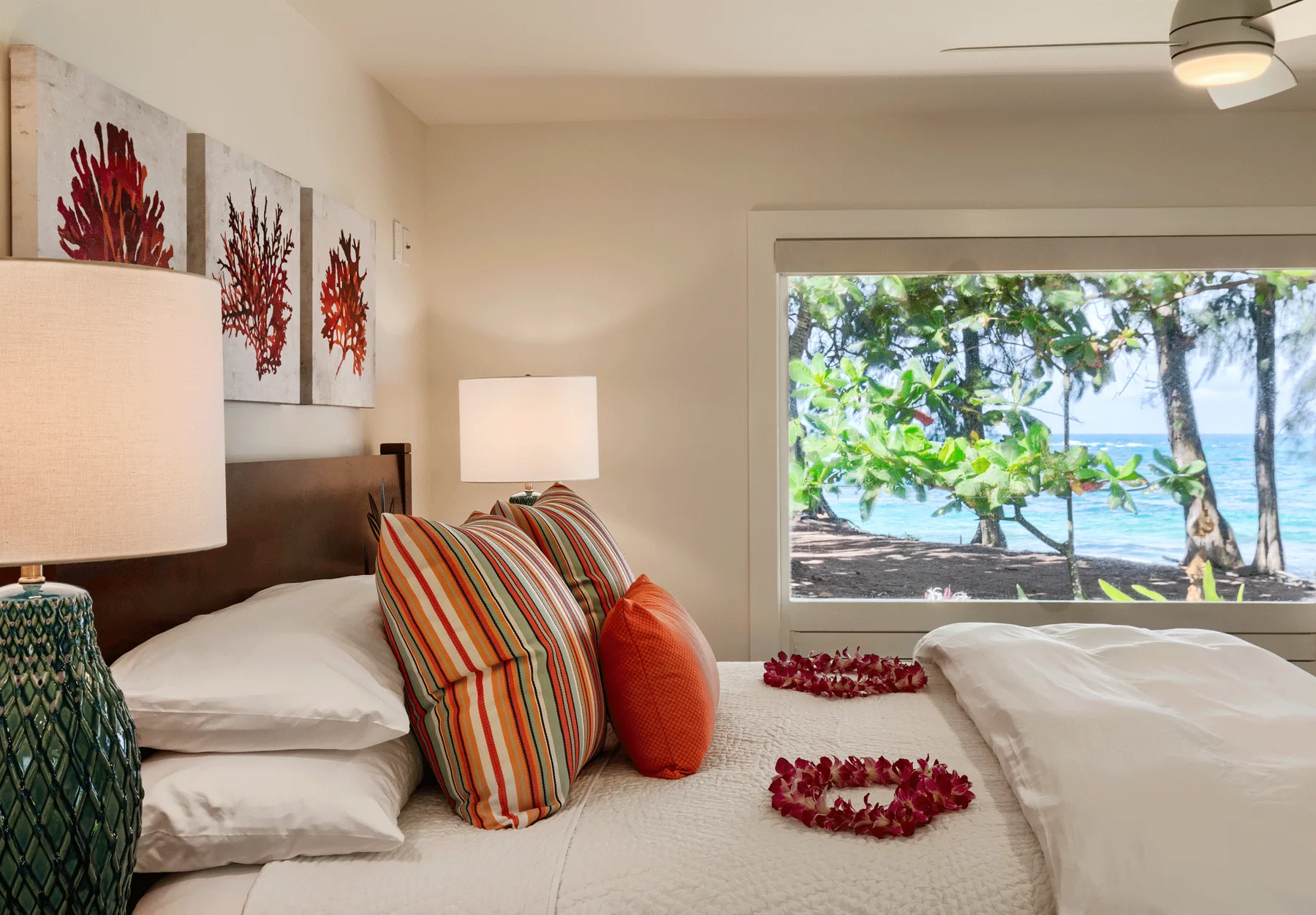 Un dormitorio con ropa de cama en capas y una gran ventana con vista al mar.