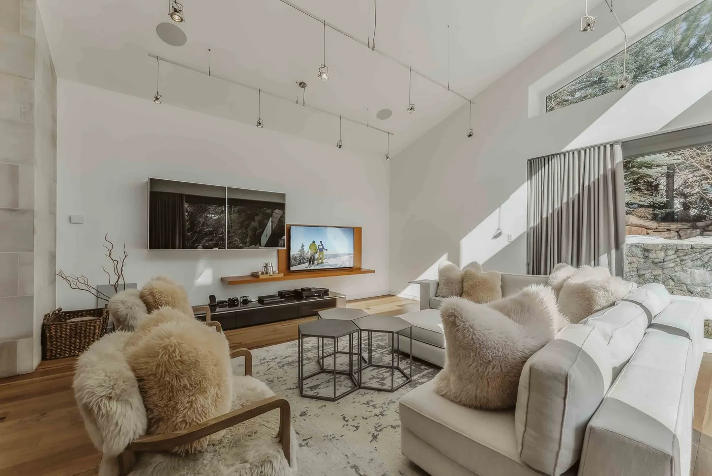 A bright living room with seating arranged around a television and coffee tables.