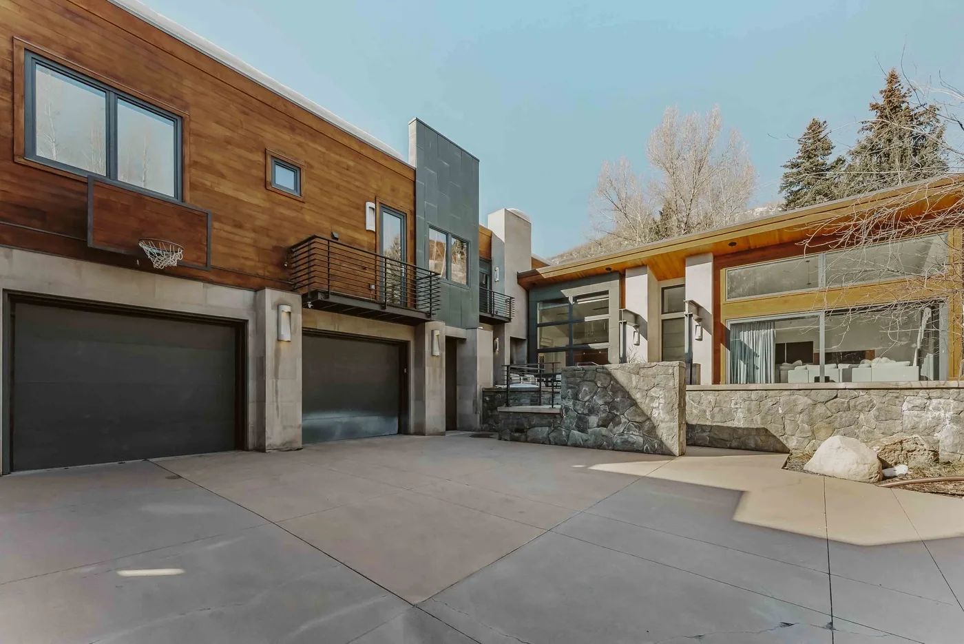 A modern house exterior with garage doors and a wide paved driveway.