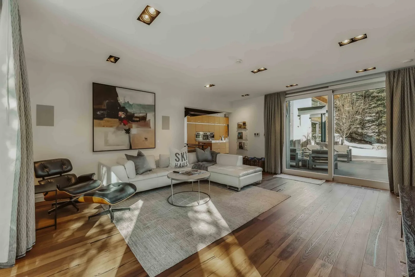 A bright living room with seating, a rug, and large glass doors.