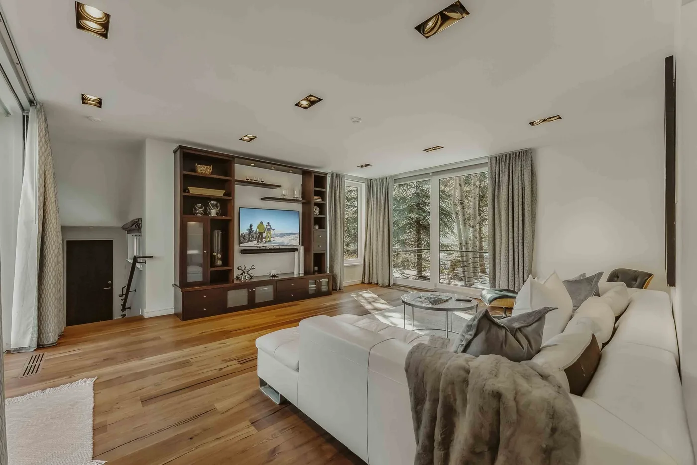 A bright living room with a large seating area and floor-to-ceiling windows.