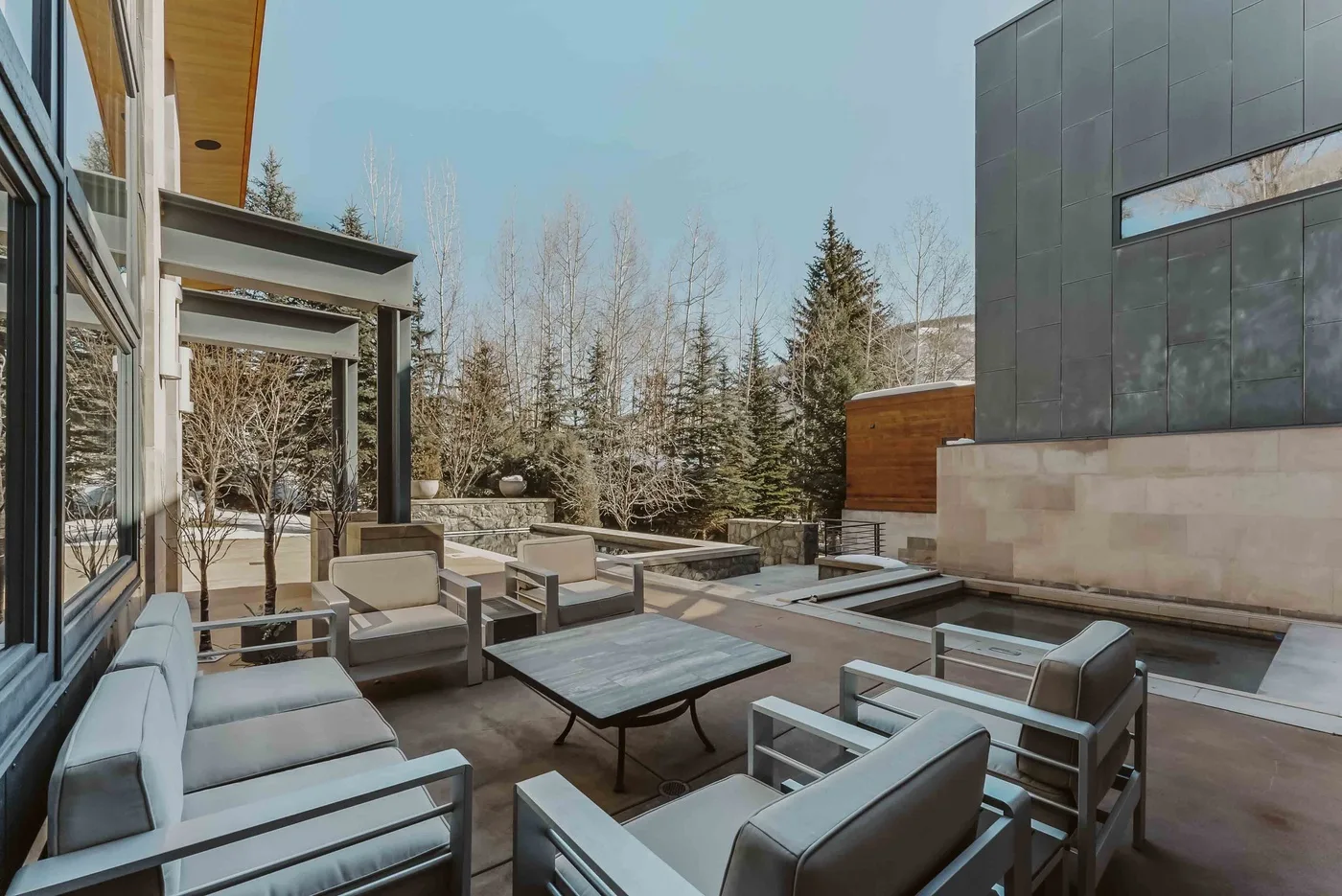An outdoor patio with seating and a low table beside a modern building.