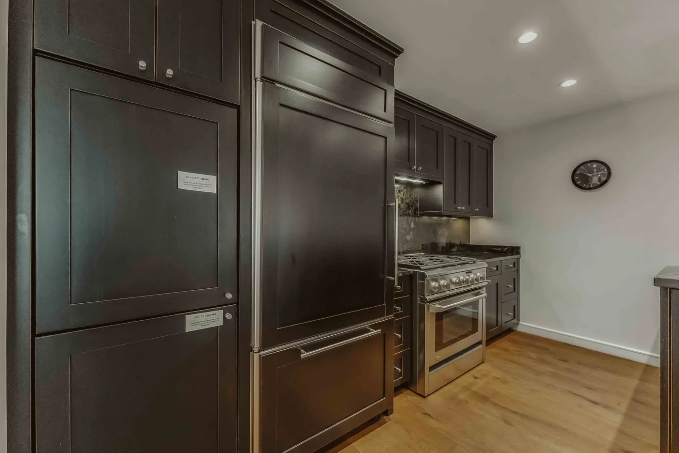 A kitchen with dark cabinetry, a range, and wood flooring.